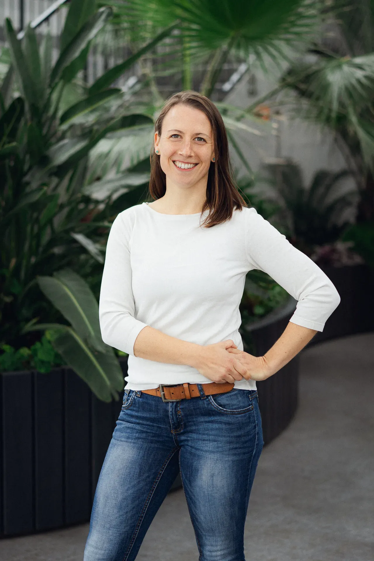 Carina Scheffler steht lächelnd vor großen grünen Pflanzen